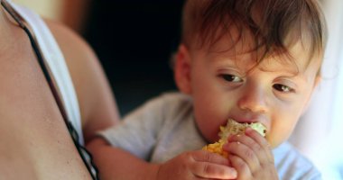 Happy baby eating corn. One year old toddler eats healthy natural snack
