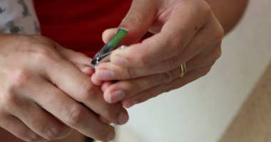 Parent trimming baby nails. Mother cutting crying infant nail