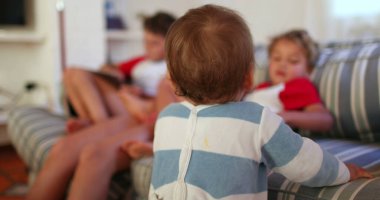 Baby infant interaction with siblings at home, candid and real. Toddler interacts with older brothers