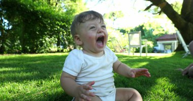 Angry baby toddler crying in outdoor home garden