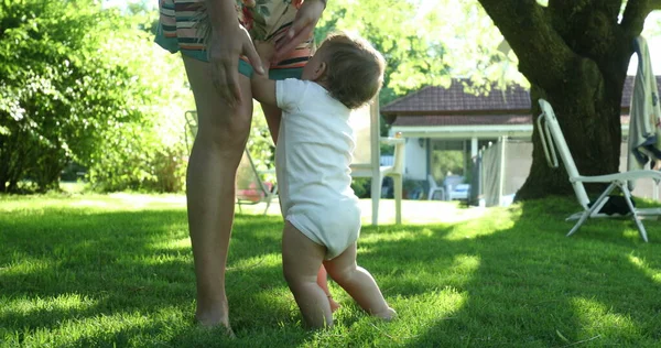 婴儿在户外抱着母亲的腿 — 图库照片