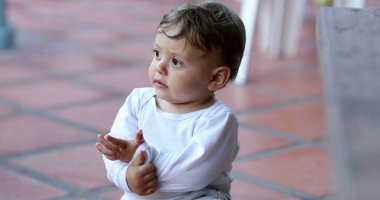 Cute baby toddler playing with sleeve. Infant crawls on floor