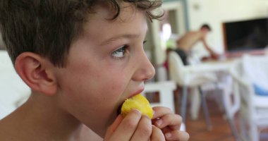 Şeftali meyvesi yiyen çocuk.