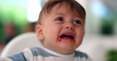 Cute baby complaining open mouth during meal