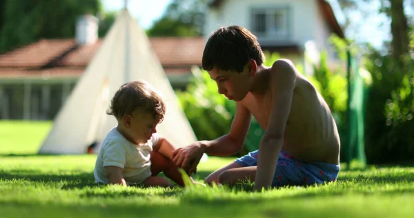 Children together in home backyard. Siblings interaction. Baby infant with older brother