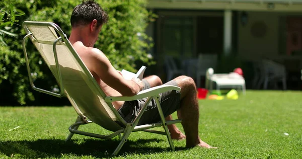 男人在自家后院看书放松 男人在户外晒太阳休息 — 图库照片