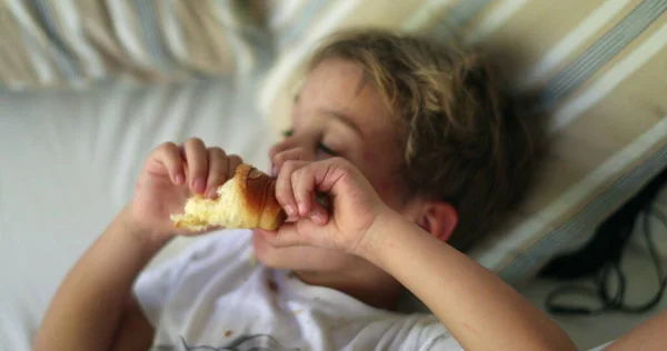 Criança Pensativa Enquanto Come Croissant Menino Deitado Sofá Contemplando Vida — Fotografia de Stock