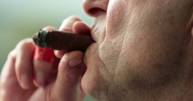 Man smoking cigar, close-up of older man mouth inhaling smoke