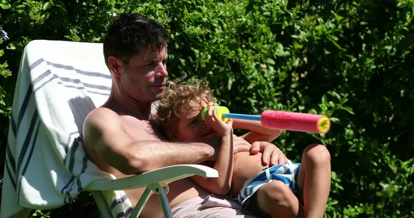 父子俩在阳光下在外面互动 Toddler躺在外面抱着爸爸的胸 — 图库照片