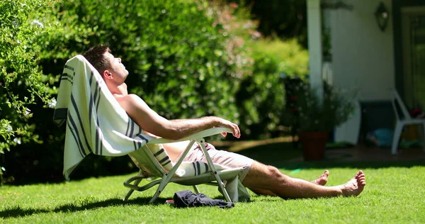 Man relaxing outside home backyard sunbathing