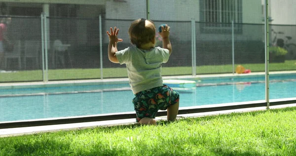 婴儿靠在游泳池栅栏上 孩子们在外面玩耍 — 图库照片