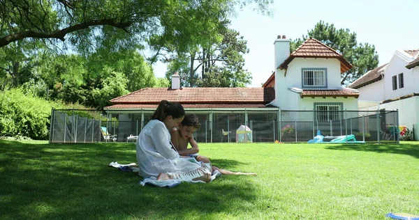 母親助けて退屈子供とともにホームワークアウト外でホーム芝生 — ストック写真