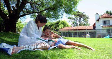 Anne ve babası çocuğuna evlerinin bahçesinde yardım ediyor. Anne çocuğa öğretiyor