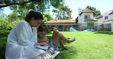 Anne, evde ev ödevi yaparken sıkılmış çocuğa yardım ediyor.