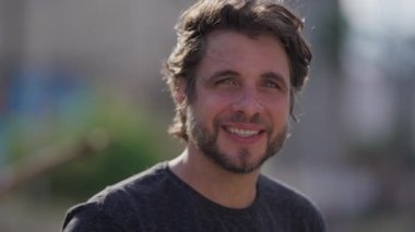 Dışarıda kameraya bakan yakışıklı bir adamın portresi. 30 'lu yaşlarda bir erkek milenyum insanı yüzünü kapatır.