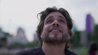 Genç bir adam gökyüzüne bakıyor. 30 'lu yaşlarda beyaz bir erkek. Yüzüne yakından bakıyor.