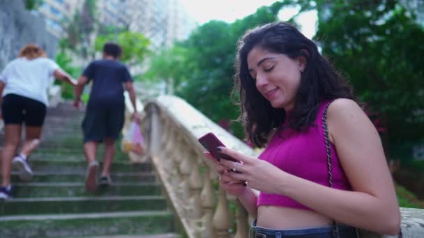 快乐的女人站在公园外的时候收到了智能手机装置上的肯定通知 一个三十来岁的女人转过头对着相机笑 — 图库视频影像
