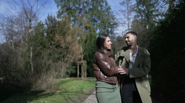 Samimi bir an. Birlikte yürüyen, gülen ve güzel bir park ortamında kucaklaşan romantik bir çift.
