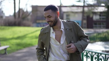 Ortadoğulu bir adam, neşe ve coşkuyla dolu güneşli bir parkta zaferden zevk alıyor.