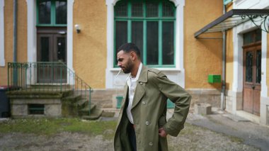 Ciddi bir Arap adam dışarıda düşünceli bir şekilde beklerken sigara yakıyor.