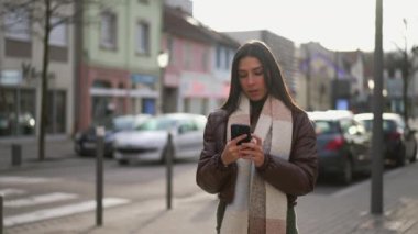 Şehir ortamında cep telefonunu kontrol eden güzel bir genç kadın.