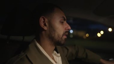 Ortadoğulu bir adam gece yolda araba sürüyor. Akşamki yolculuktaki erkek şahsın düşünceli yüz ifadesiyle profil fotoğrafı.