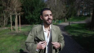 Kaygısız mutlu genç adam, güneşli bir günde parkta mola verip doğanın tadını çıkarıyor.