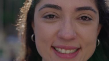 30 'lu yaşlarda, mutlu bir ifadeyle kameraya gülümseyen bir kadının aşırı yakın yüzü.