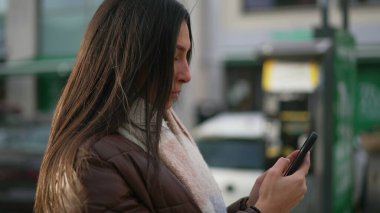 Şehir ortamında cep telefonunu kontrol eden güzel bir genç kadın.