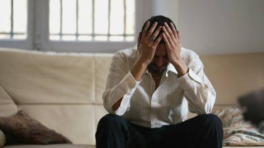 Dramatik genç adam duygusal baskı yüzünden perişan ve stresli hissediyor. Hüsrana uğramış erkek, evinde oturup koltuğa vurarak agresif davranıyor.