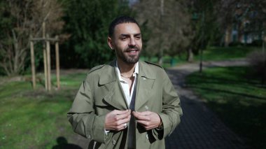 Kaygısız mutlu genç adam, güneşli bir günde parkta mola verip doğanın tadını çıkarıyor.