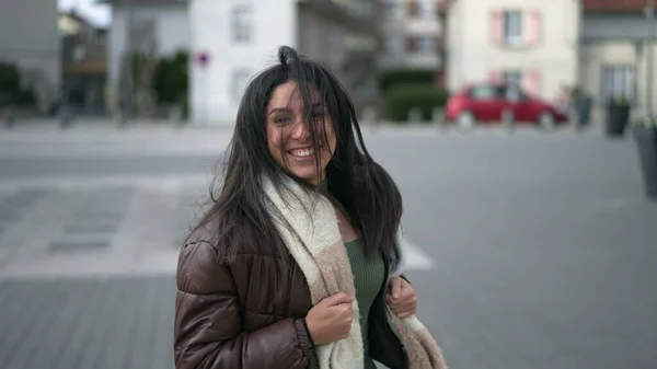 都会の道を走りながらカメラに向かってゆっくりと動きながら微笑む幸せな若い女性 — ストック写真