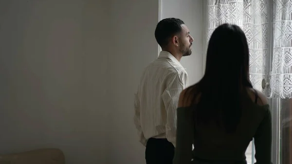 stock image Boyfriend in silence while girlfriend makes of fun of his calm demeanor. Back of woman gesturing to man who stands by window at home