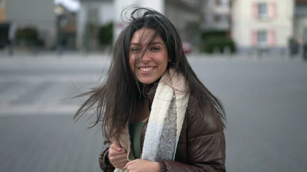 都会の道を走りながらカメラに向かってゆっくりと動きながら微笑む幸せな若い女性 — ストック写真