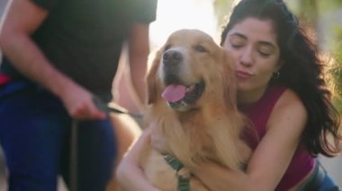 Parkta Golden Retriever köpeğini kucaklayan bir kadın. Hafta sonu eğlenen bir çift. İnsanlar gün ışığında evcil hayvanlara sarılır.