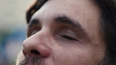 Açık havada tefekküre dalmış ruhani bir adam. 30 'lu yaşlarda bir adamın yakın plan yüzü dikkatle gözlerini kapatır ve sonra umutla ve inançla gökyüzüne bakıp gülümser.