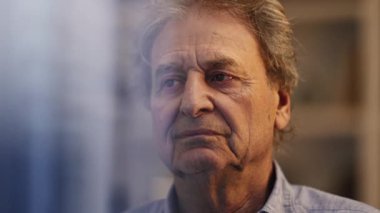 Düşünceli bir kıdemli adam pencere yansımasından görünen hayatı düşünüyor. Gece 70 'li yaşlarda meditasyon yapan yaşlı bir erkek.