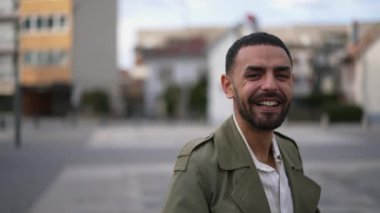 Şehir ortamında dururken gülümseyen ve gülen neşeli bir Arap portresi