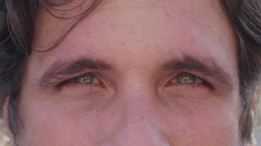 Ciddi bir adam kameraya surat asıyor. Erkek görüşü makro yakın çekim kameraya bakıyor.