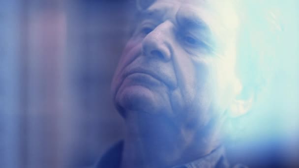 沉思的老人陷入沉思 凝视着窗外的世界 一位70多岁的老先生带着严肃的表情沉思着人生的意义 — 图库视频影像