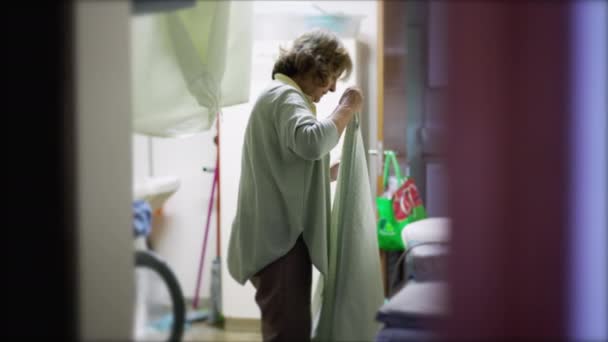 高效和独立 老太太在洗衣房处理家务事 老年人折叠床单的日常家庭作息和正宗 — 图库视频影像
