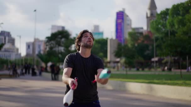 男性ジャグラーは 都市公園の外で彼のスキルを実証します 空気中の物体をジャグリングする人 — ストック動画