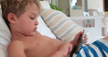 Boy lying on sofa using smartphone