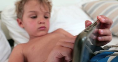 Çocuk akıllı telefon cihazı tutuyor, çocuk cep telefonu teknolojisiyle video oyunu oynuyor.