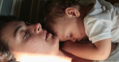 Yorgun bir anne bebek bebekle yatıyor.