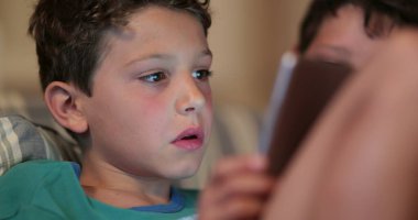 Geceleri tablet kullanan yakışıklı bir genç. Çoklu görev yapan, TV izleyen ve oyun oynayan çocuklar