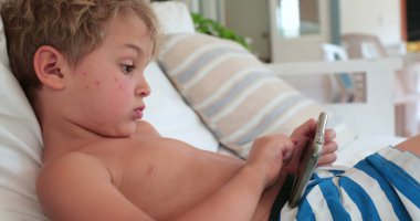 Boy lying on sofa using smartphone