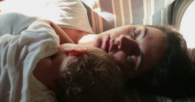 Candid woman hugging baby infant at home asleep
