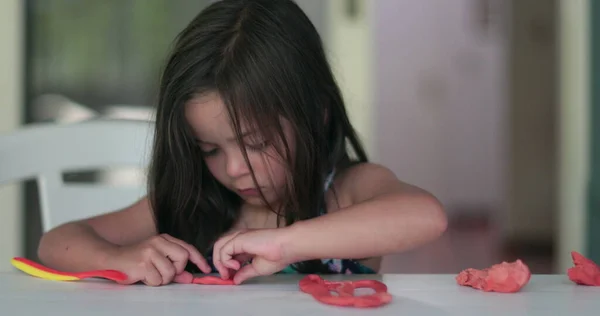 Child girl playing with play dough, kid creating with plasticine