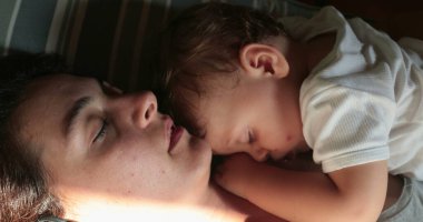 Anne bebeğiyle yatıyor. Dürüst, yorgun ve yorgun ebeveyn uykuda.